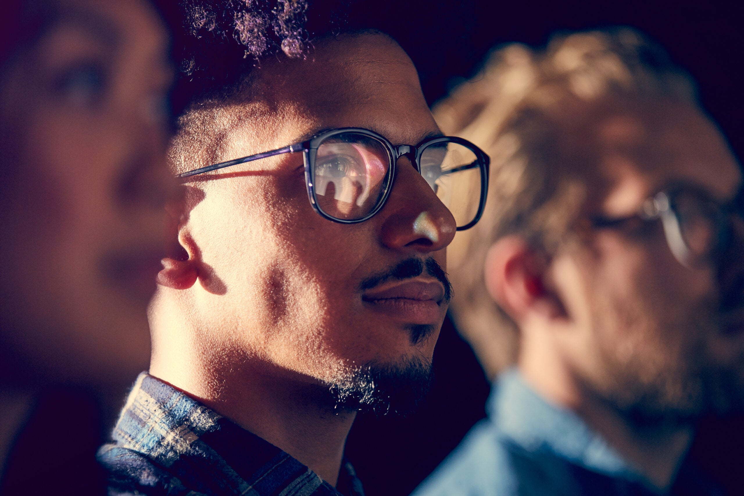 Three people standing in a row, the middle person is in focus.