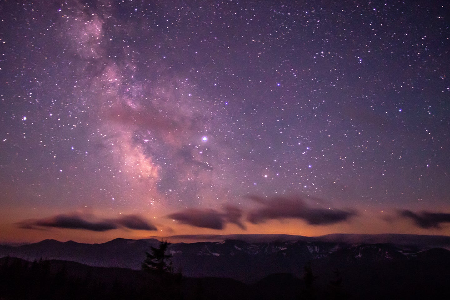 A night sky over mountains.